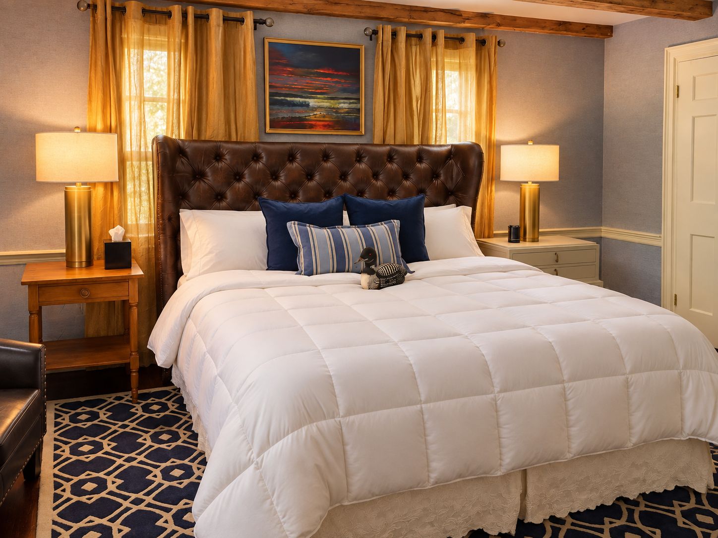 A hotel room with a large bed, two bedside tables, a nightstand, a decorative rug, and a painting on the wall.