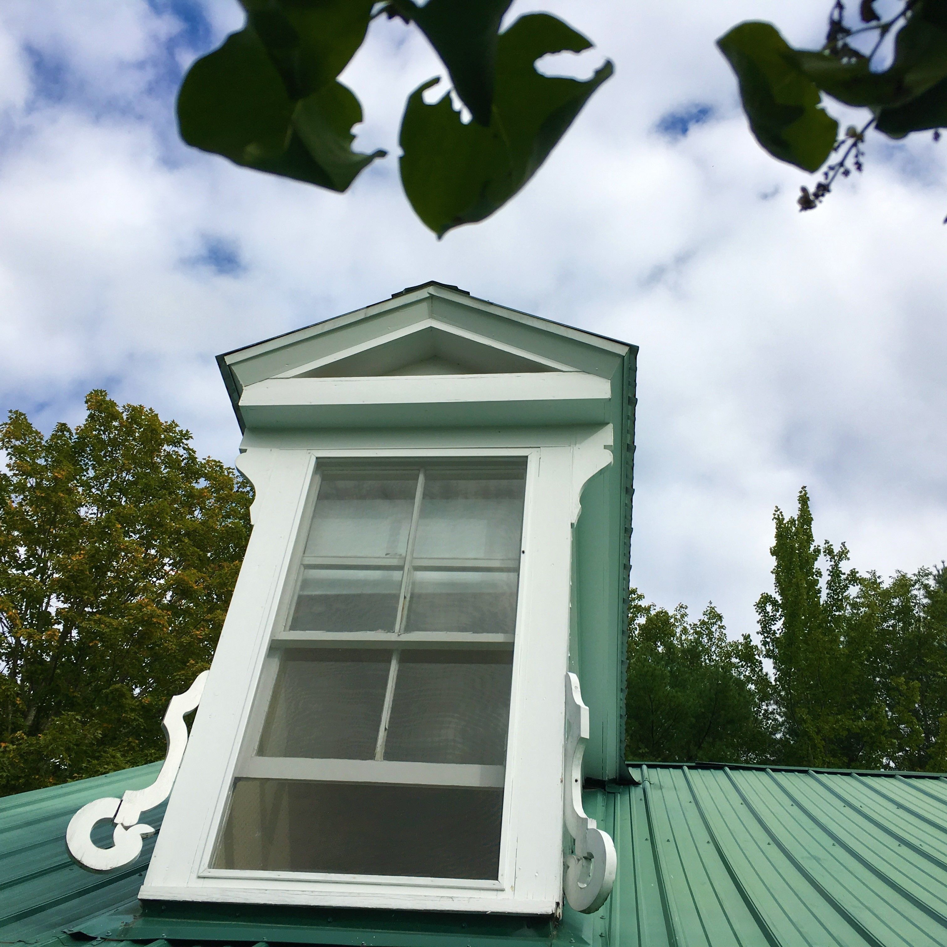 A dormer window with a white frame and a green roof.