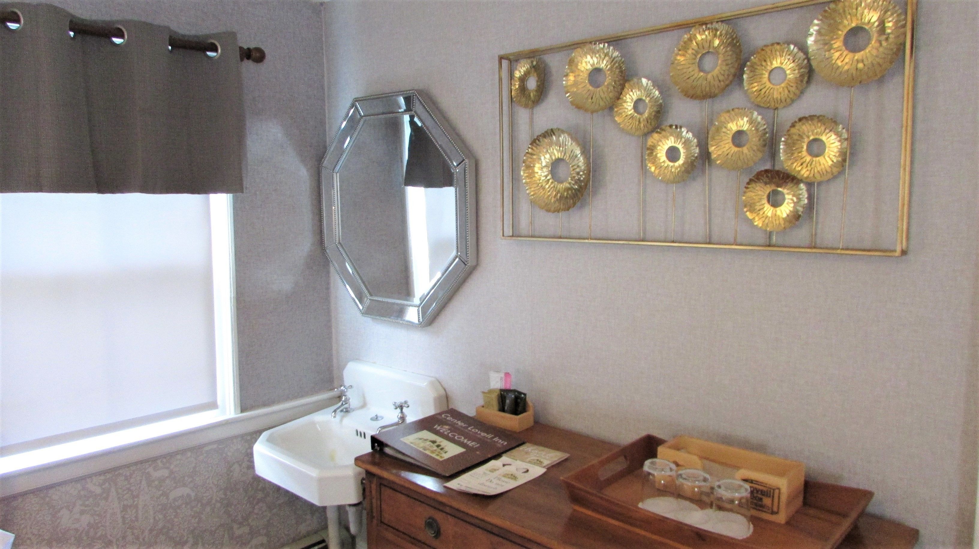 A bathroom with a sink, mirror, and decorative wall art.