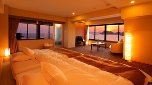 Quarto de hotel com uma cama grande, uma escrivaninha, uma cadeira e vista para o mar.