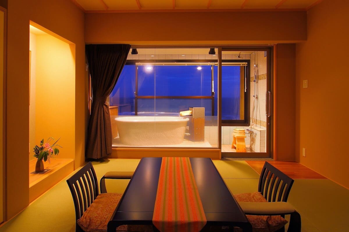 A modern room with a large sliding glass door leading to a balcony with a blue sky view.