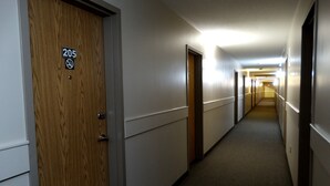 A hotel hallway with doors marked 205, a carpeted floor, and a light source at the end. - R&R Inn (Provost)