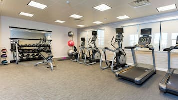 A gym with treadmills, elliptical machines, and free weights.