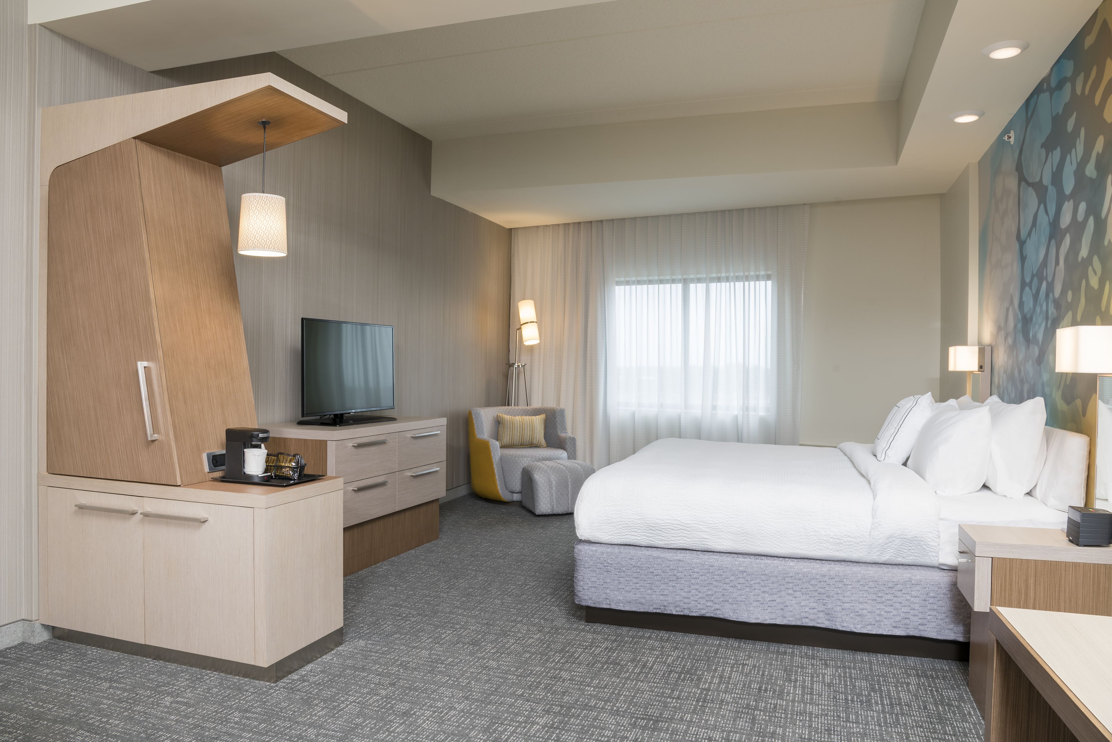 Una habitación de hotel con una cama, televisión, escritorio y una silla.