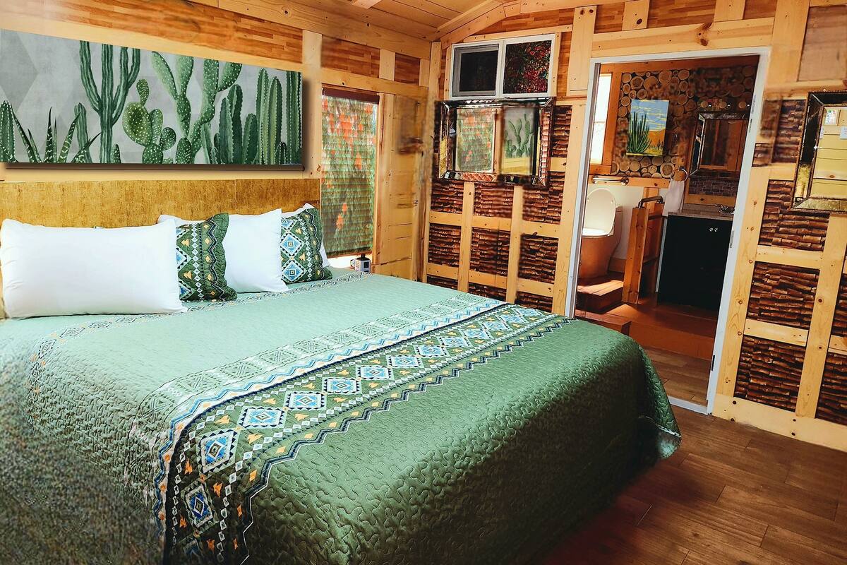 A room with a bed, a television, and a bathroom visible through an open door.