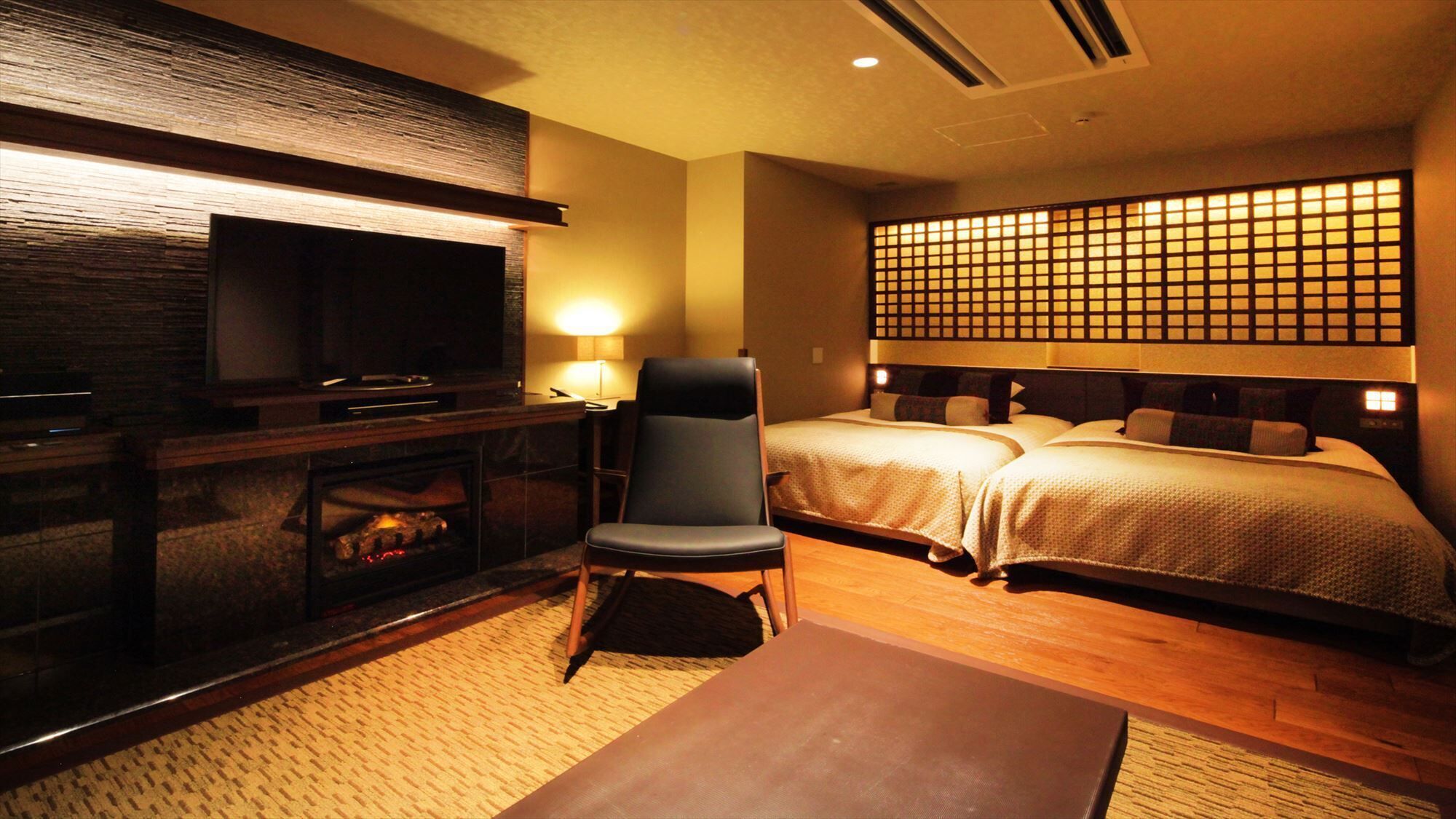 Habitación de hotel con televisión, una silla, una cama y una pared con diseño de cuadrícula.