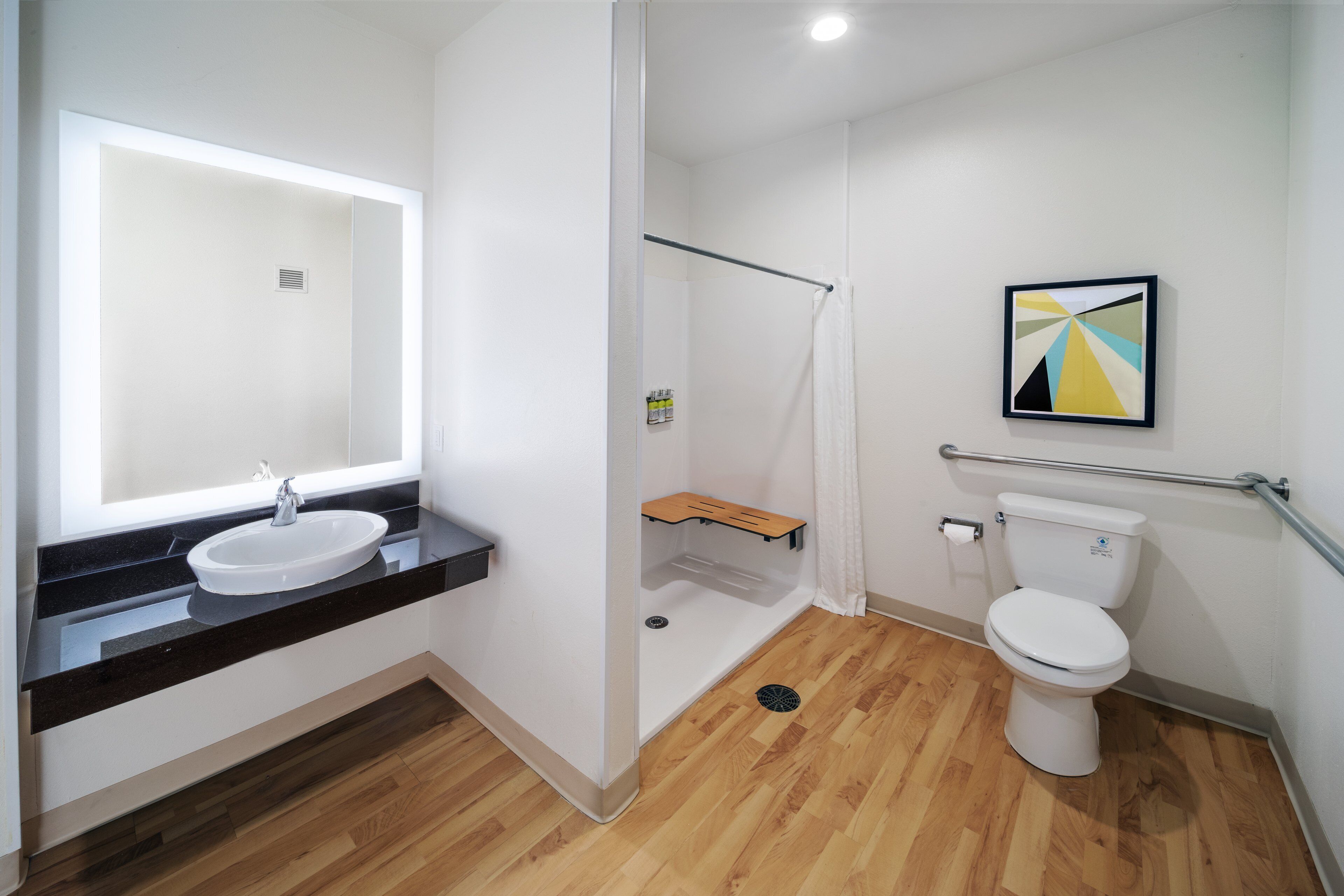Un baño moderno con lavamanos, espejo, ducha e inodoro.