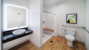 Un baño moderno con lavamanos, espejo, ducha e inodoro.