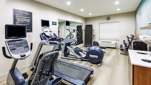 A fitness center with treadmills, elliptical machines, and a weight bench.