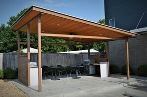 An outdoor patio with a wooden roof, a grill, and seating. - Candlewood Suites Muskogee by IHG (Muskogee)
