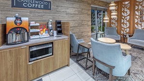 A modern coffee shop interior with a coffee machine, seating area, and a sign reading "Candlewood Coffee".