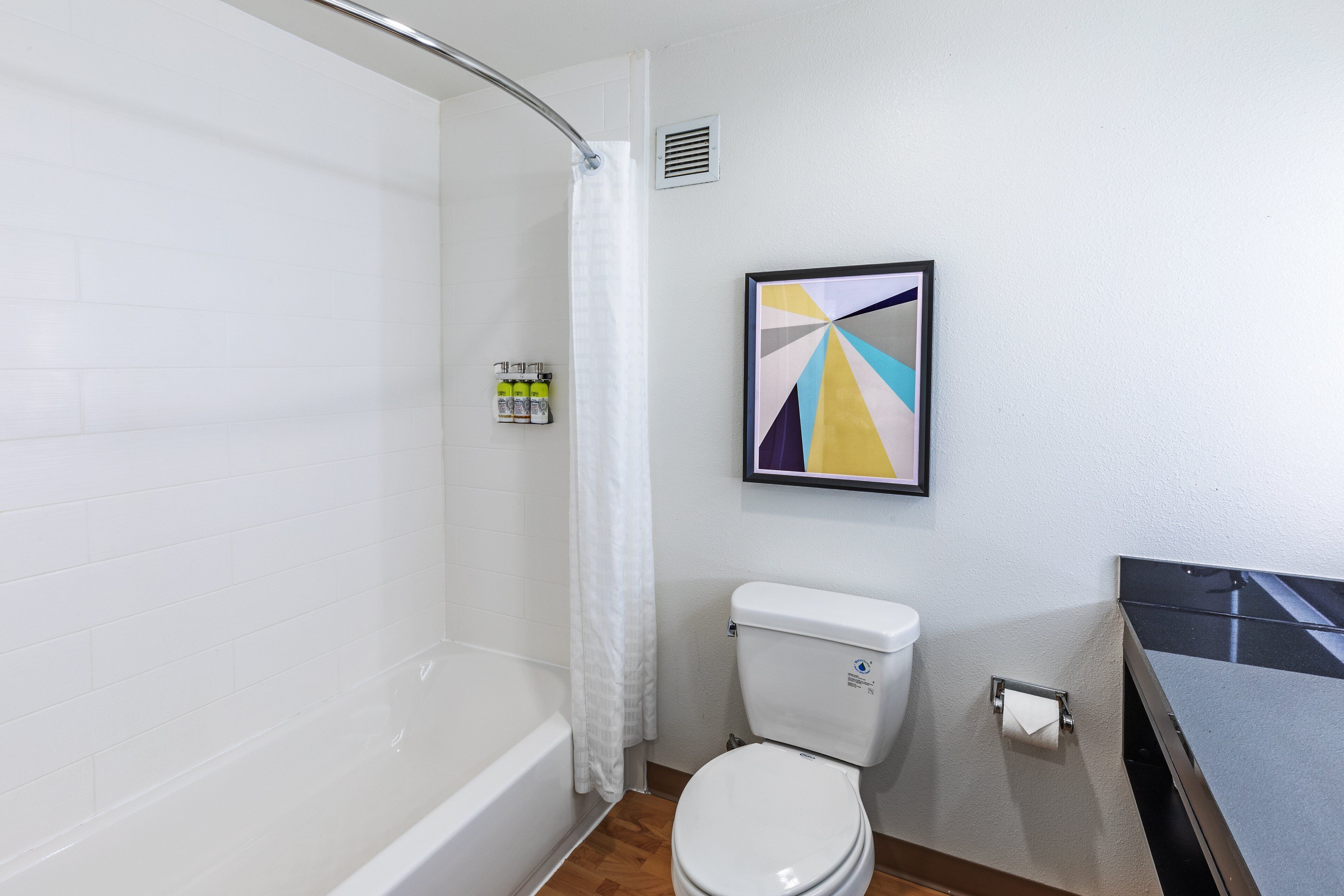 A bathroom with a bathtub, toilet, and a shower curtain.