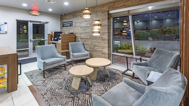 A modern coffee shop interior with seating, a coffee machine, and a view of the street outside.