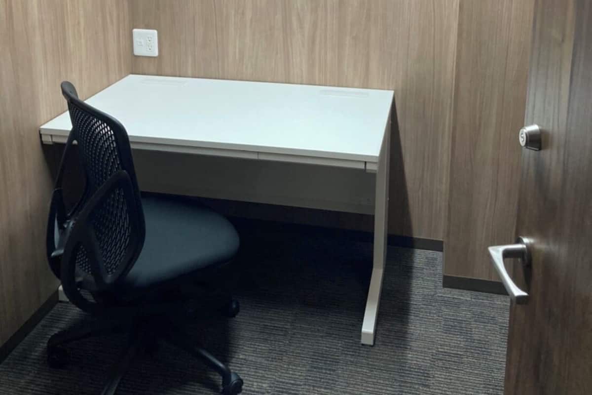 A small office space with a white desk, a black office chair, and a door.