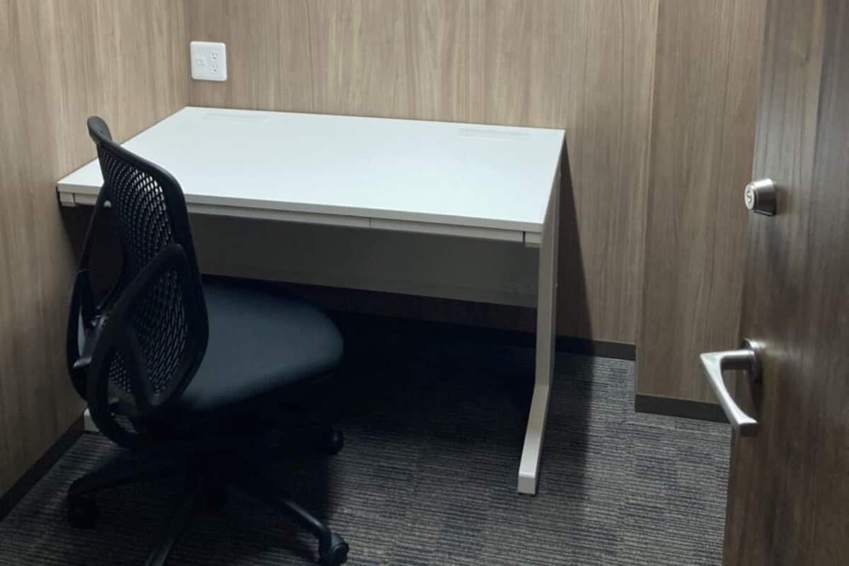 A small office space with a white desk, a black office chair, and a door.