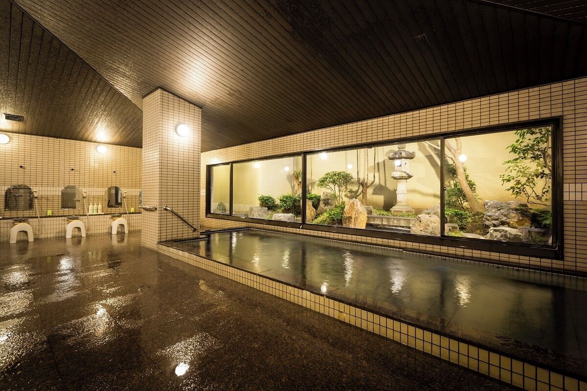 A wet pool area with tiled walls and a large window with a view of rocks and plants.