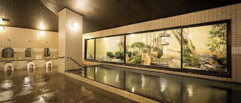 A wet pool area with tiled walls and a large window with a view of rocks and plants.
