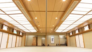 A traditional Japanese room with tatami flooring, sliding doors, and a wooden ceiling with skylights. - Hanazono Kaikan (Kyoto)