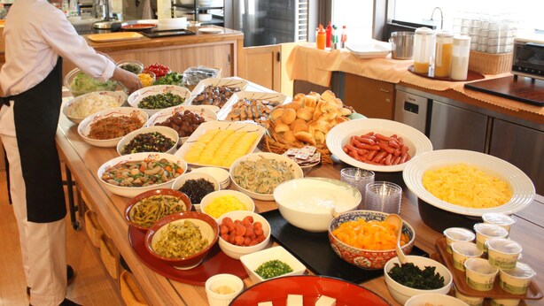 Een buffet met diverse gerechten en iemand die eten serveert.