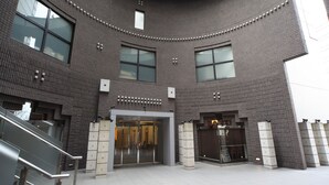 Een modern gebouw met een golvende gevel, grote ramen en een centrale ingang met glazen deuren.