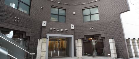 A modern building with a curved facade, large windows, and a central entrance with glass doors.