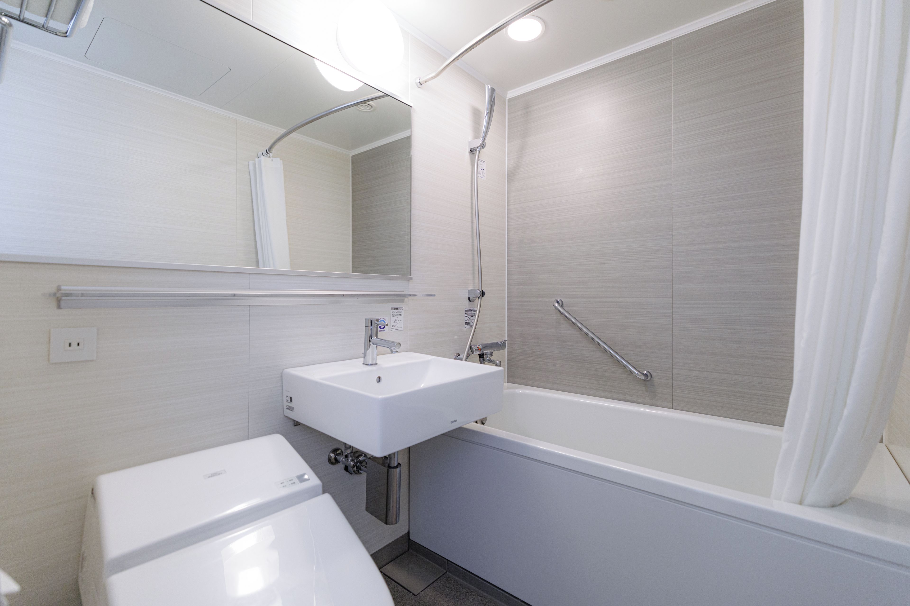 A modern bathroom with a white sink, mirror, and bathtub.