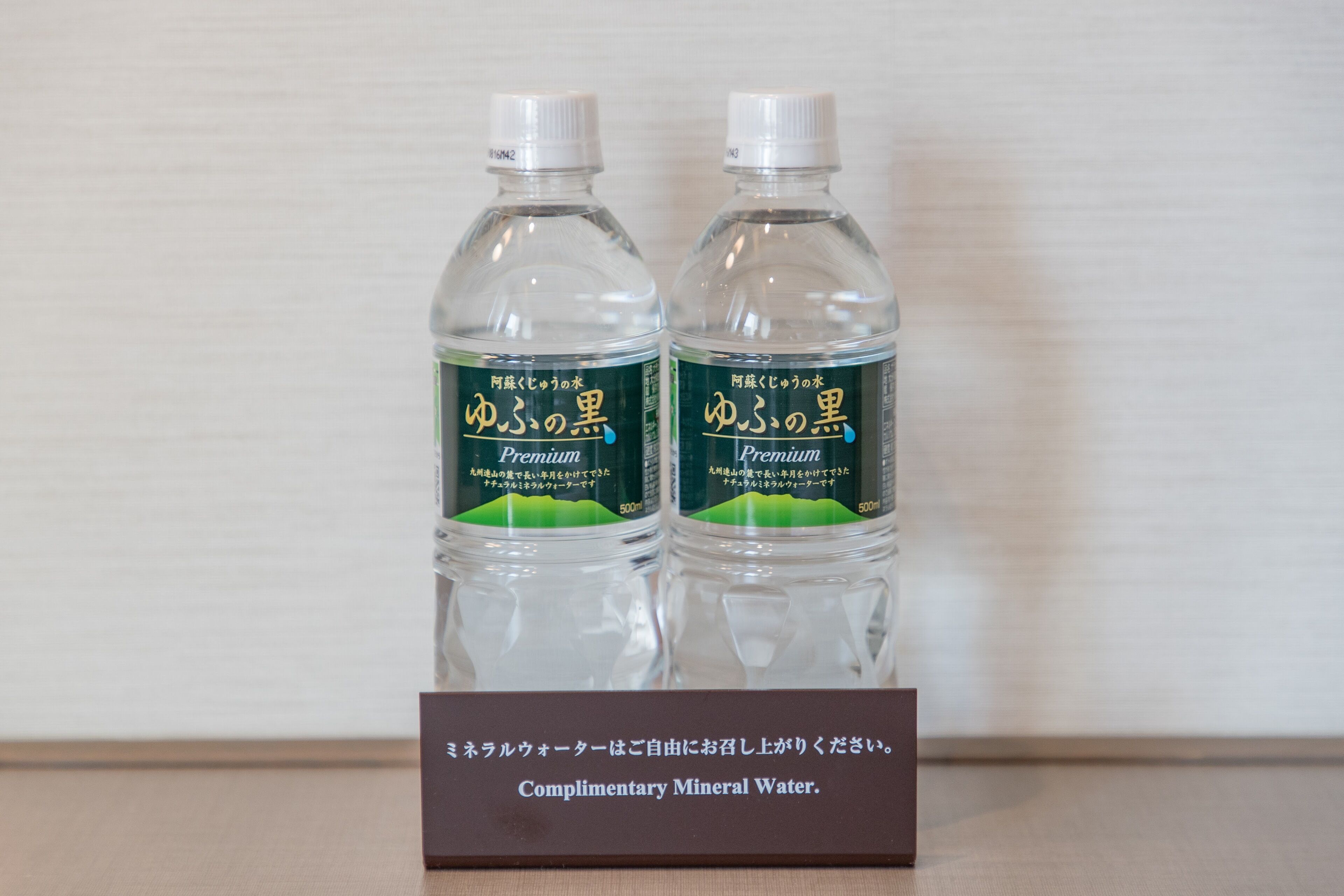 Dos botellas de agua con la etiqueta "Premium" y un cartel que indica "Agua mineral de cortesía".