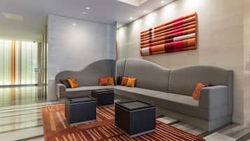 A modern lobby with a grey sofa, black side tables, and a patterned rug.