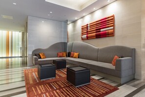 A modern lobby with a grey sofa, black side tables, and a patterned rug.