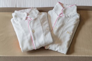 Two neatly folded white shirts with pink piping and buttons, placed on a wooden surface. - JR KYUSHU HOTEL Blossom Hakata Chuo (Fukuoka)