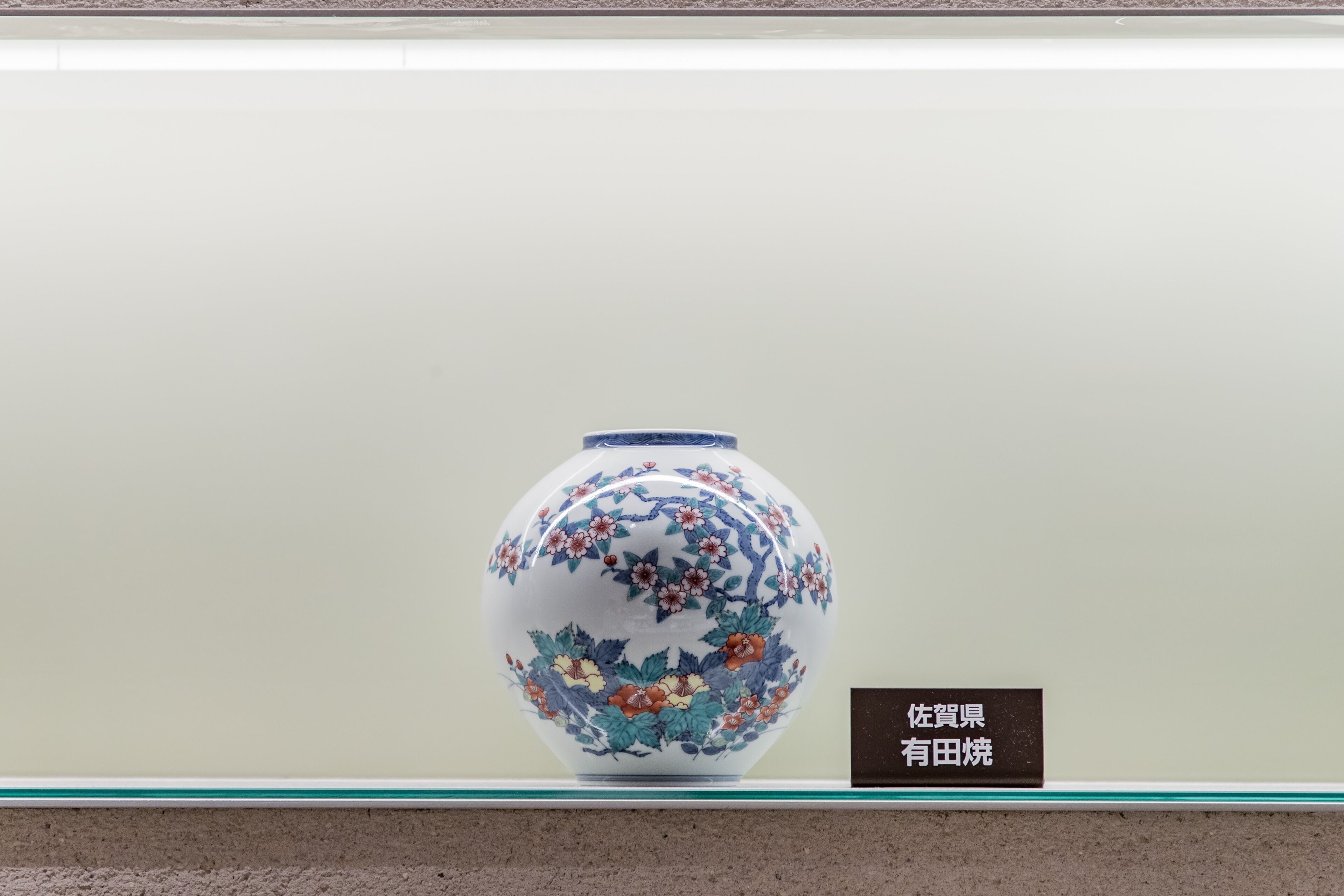 A ceramic vase with floral designs on display against a plain background.