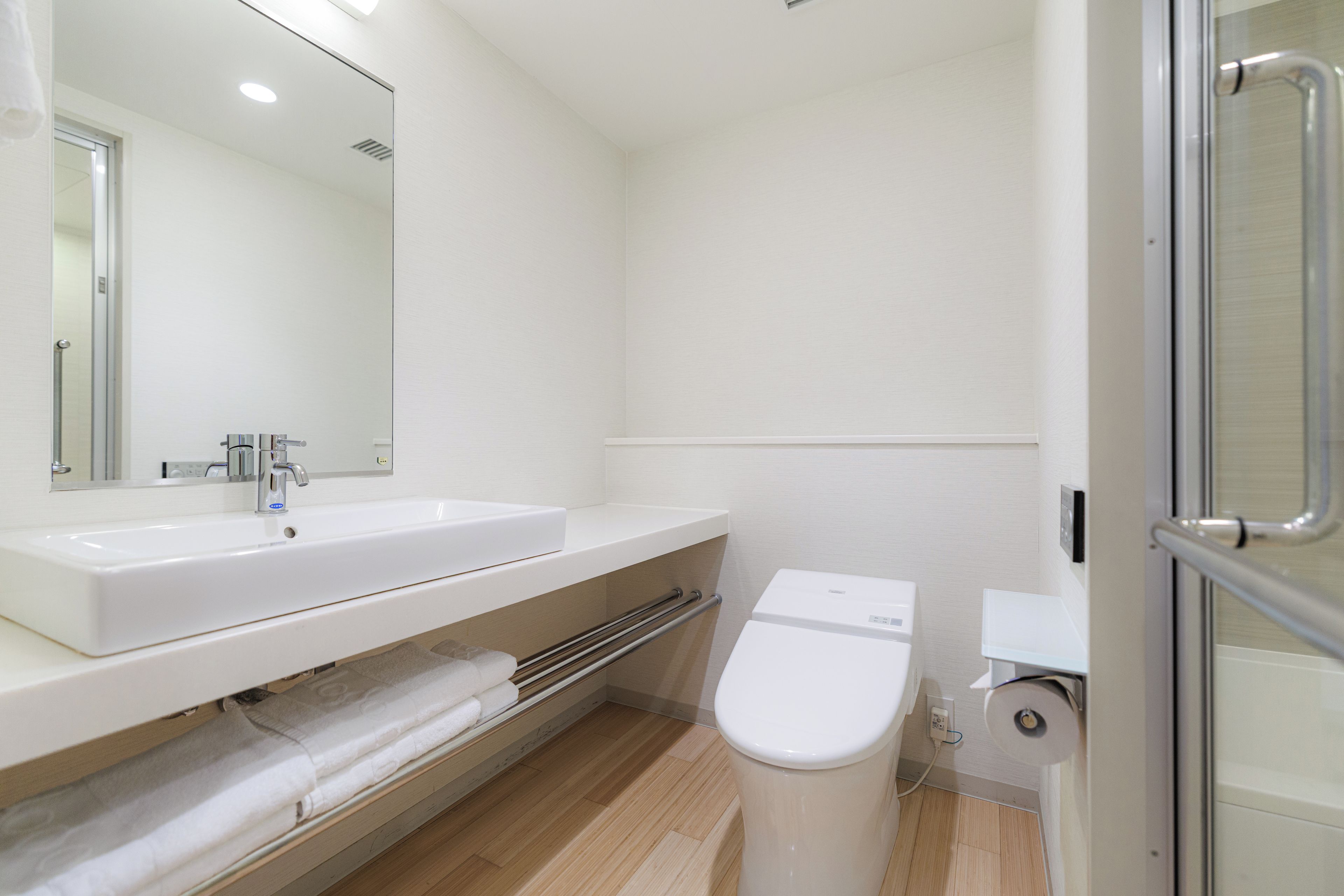 A modern bathroom with a white sink, mirror, and toilet.