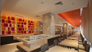 Een modern restaurant met een centraal eiland, verschillende zithoeken en een levendige wanddecoratie.