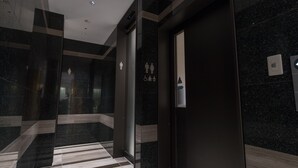 Een moderne lift met een marmeren wand en een gestreept vloertje.