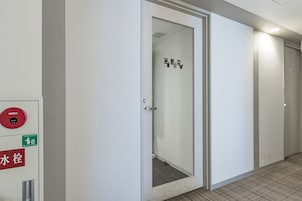 A hallway with a door leading to a room, a fire alarm, and a water emergency sign.
