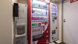 Un distributeur automatique orné du logo Coca-Cola, un autre de la marque Kirin et un distributeur d’eau.