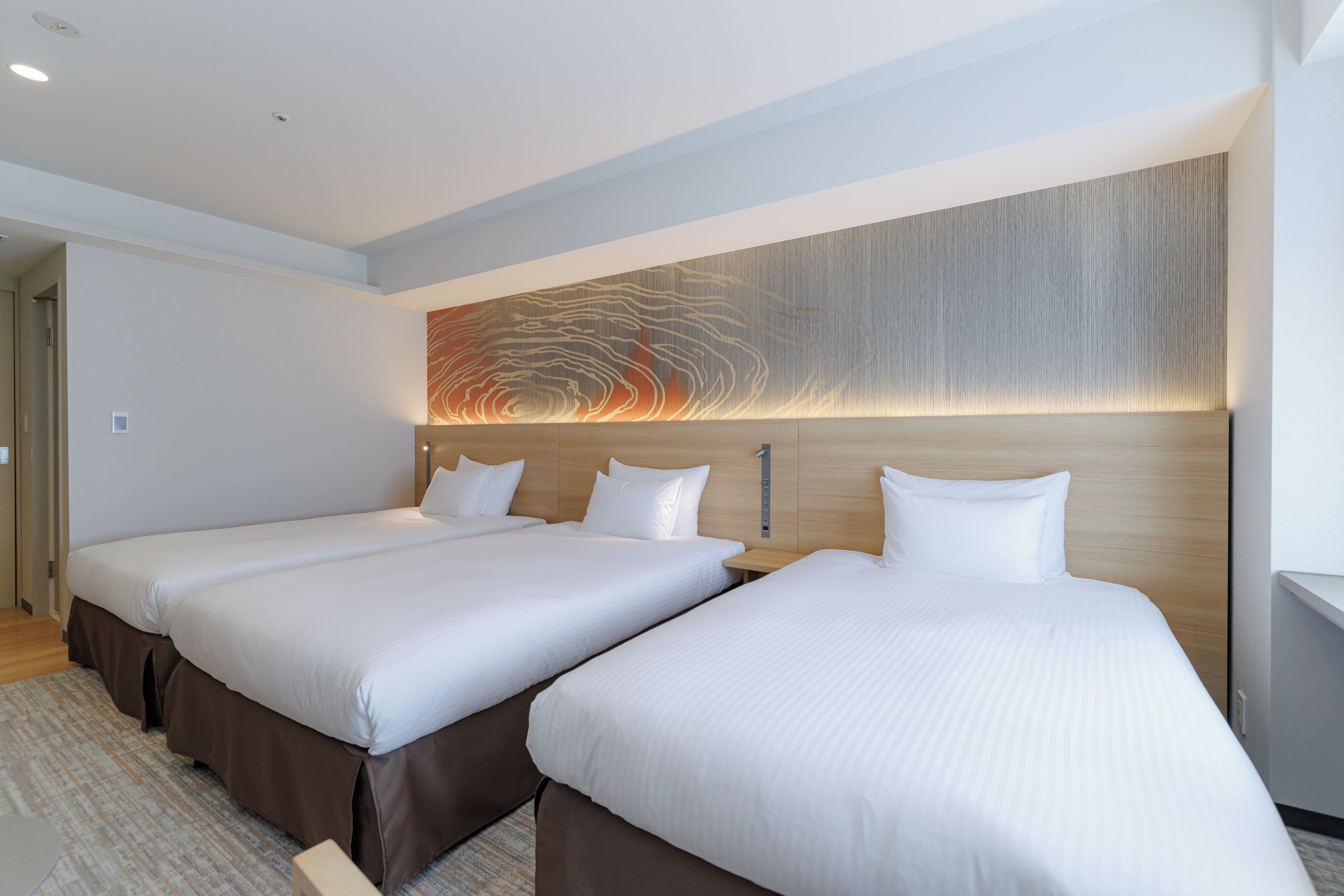 A hotel room with two beds, a large abstract wall art, and a modern design.