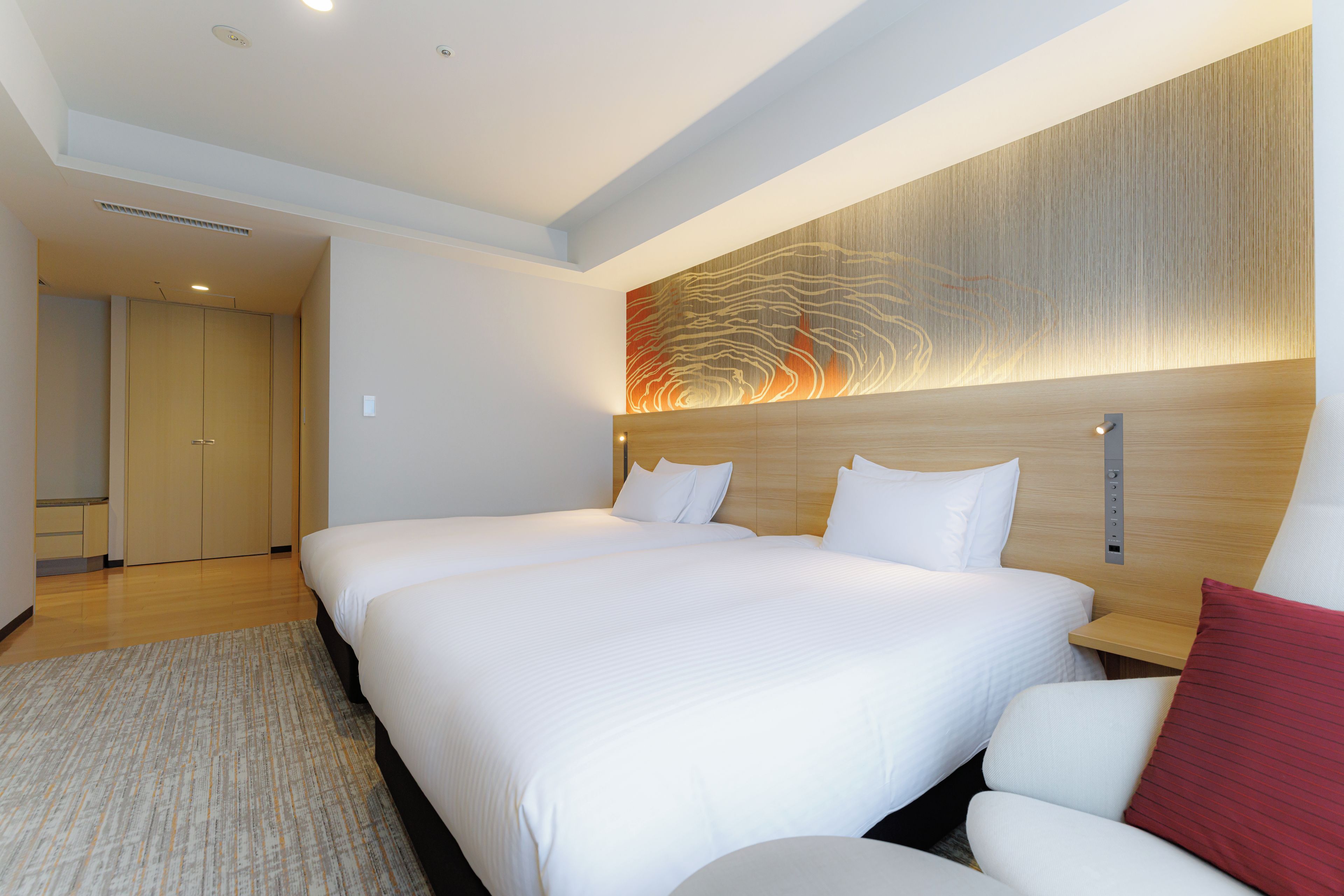 A hotel room with a large bed, a wooden headboard, and a modern wall art piece.