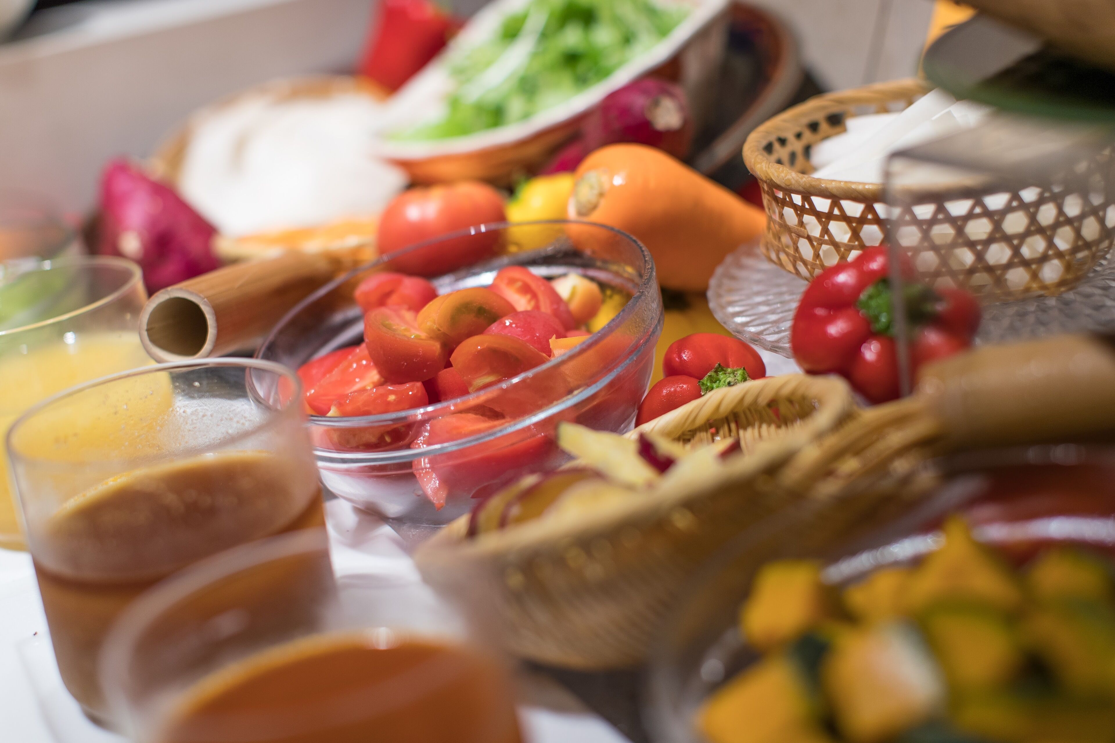 A buffet table with various food items including fruits, vegetables, and a glass of juice.