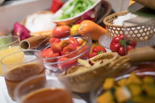 A buffet table with various food items including fruits, vegetables, and a glass of juice.