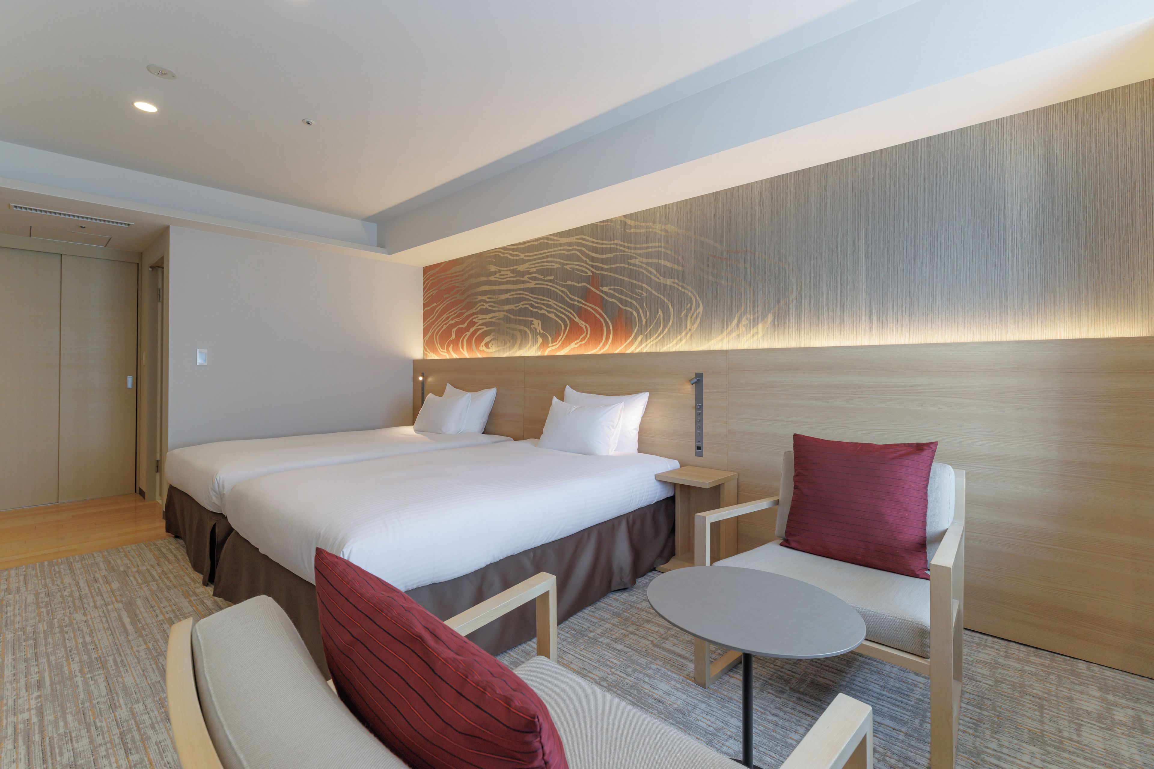 Une chambre d’hôtel avec un grand lit, une table de chevet, une chaise et une petite table ronde.