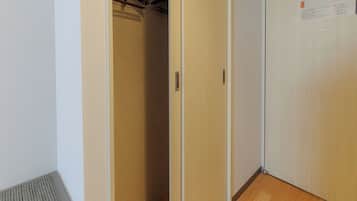 A narrow hallway with a wooden floor, a door with a sign, and a ceiling with exposed beams.