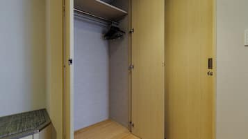 A room with a wooden floor, a closed door, and a closet with a hanging rod.