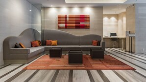 Een moderne woonkamer met een modulaire bank, twee zwarte bijzettafels en een kamerbreed tapijt met patroon.