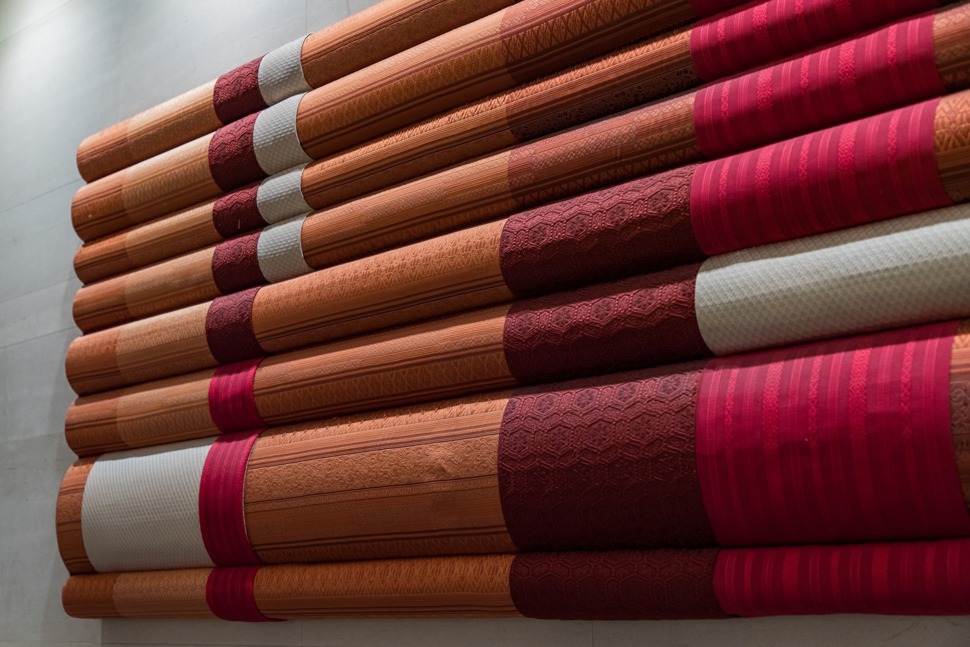 A stack of rolled carpets with various patterns and textures.