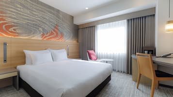 A hotel room with a large bed, a desk, a chair, and a view of the outdoors through the window.
