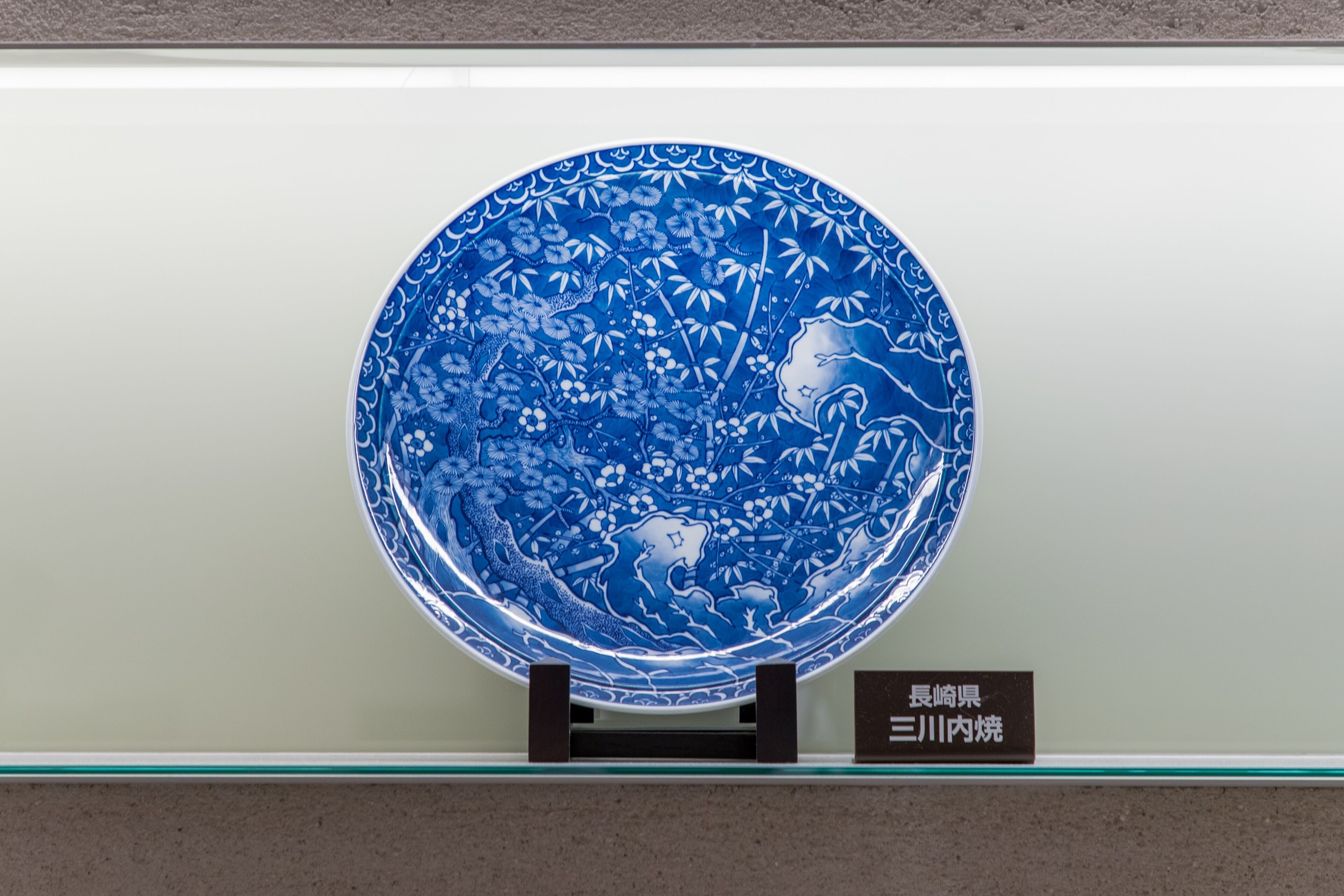 A blue ceramic plate with floral patterns on display.
