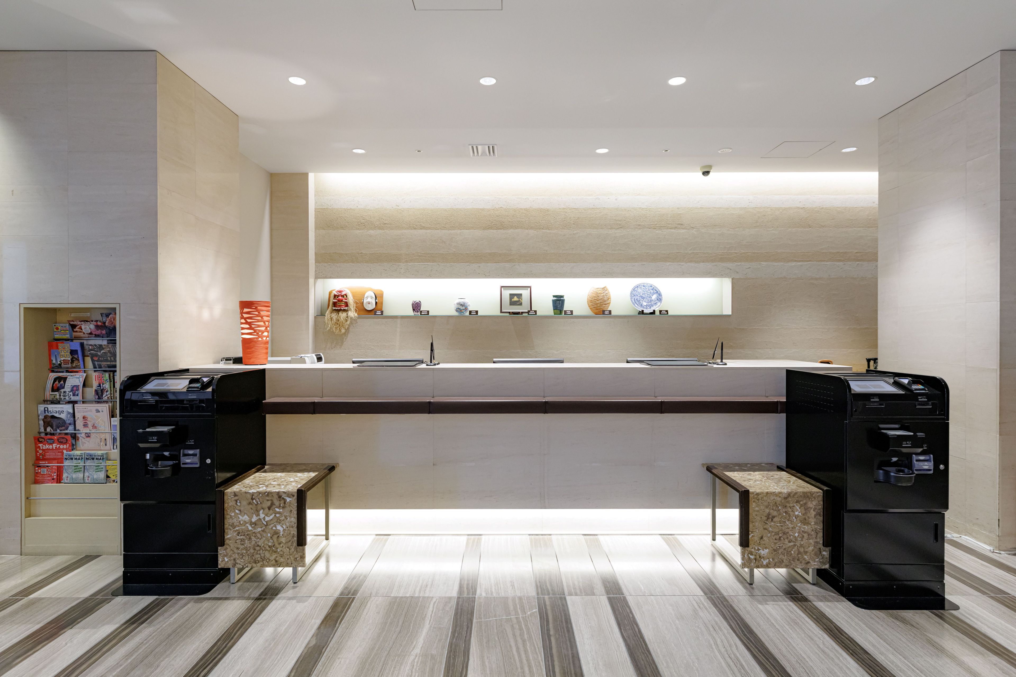 Un espace d’accueil moderne comprenant un comptoir, deux imprimantes et une présentation d’objets décoratifs.