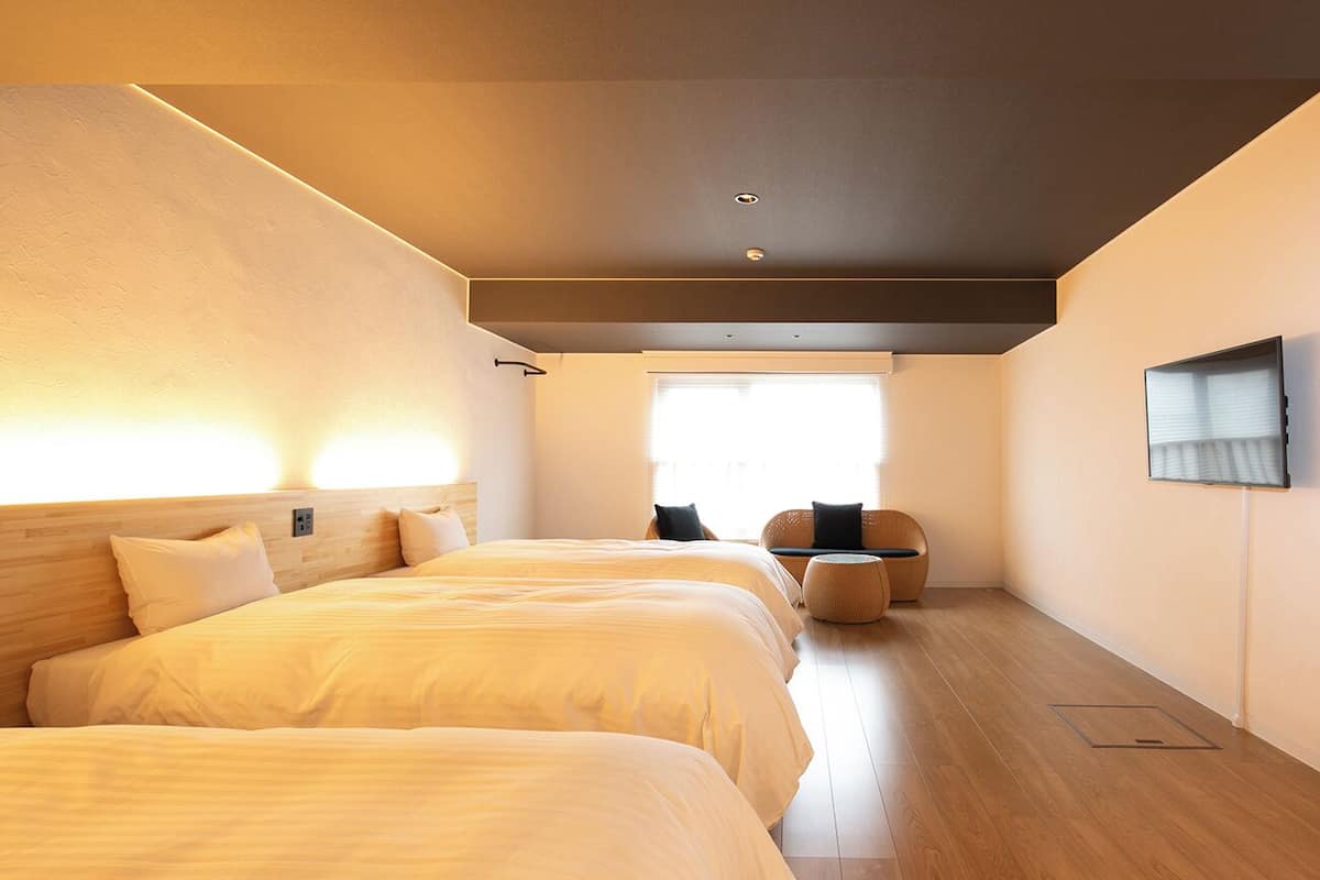 Hotelkamer met twee bedden, een zithoek, een televisie en een raam met jaloezieën.