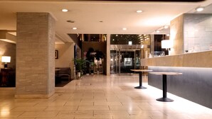 A modern lobby with a reception desk, seating area, and a staircase leading to an upper level. - Kochi Sunrise Hotel (Kochi)